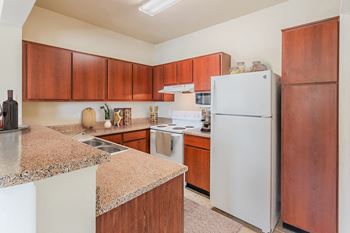 a kitchen with white appliances and granite counter tops at Lakeside Pointe Apartments & Townhomes, Texas